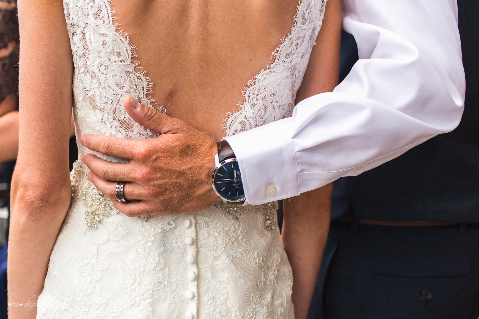 lake-tahoe-wedding-grooms-hand-on-brides-back-lace-dress