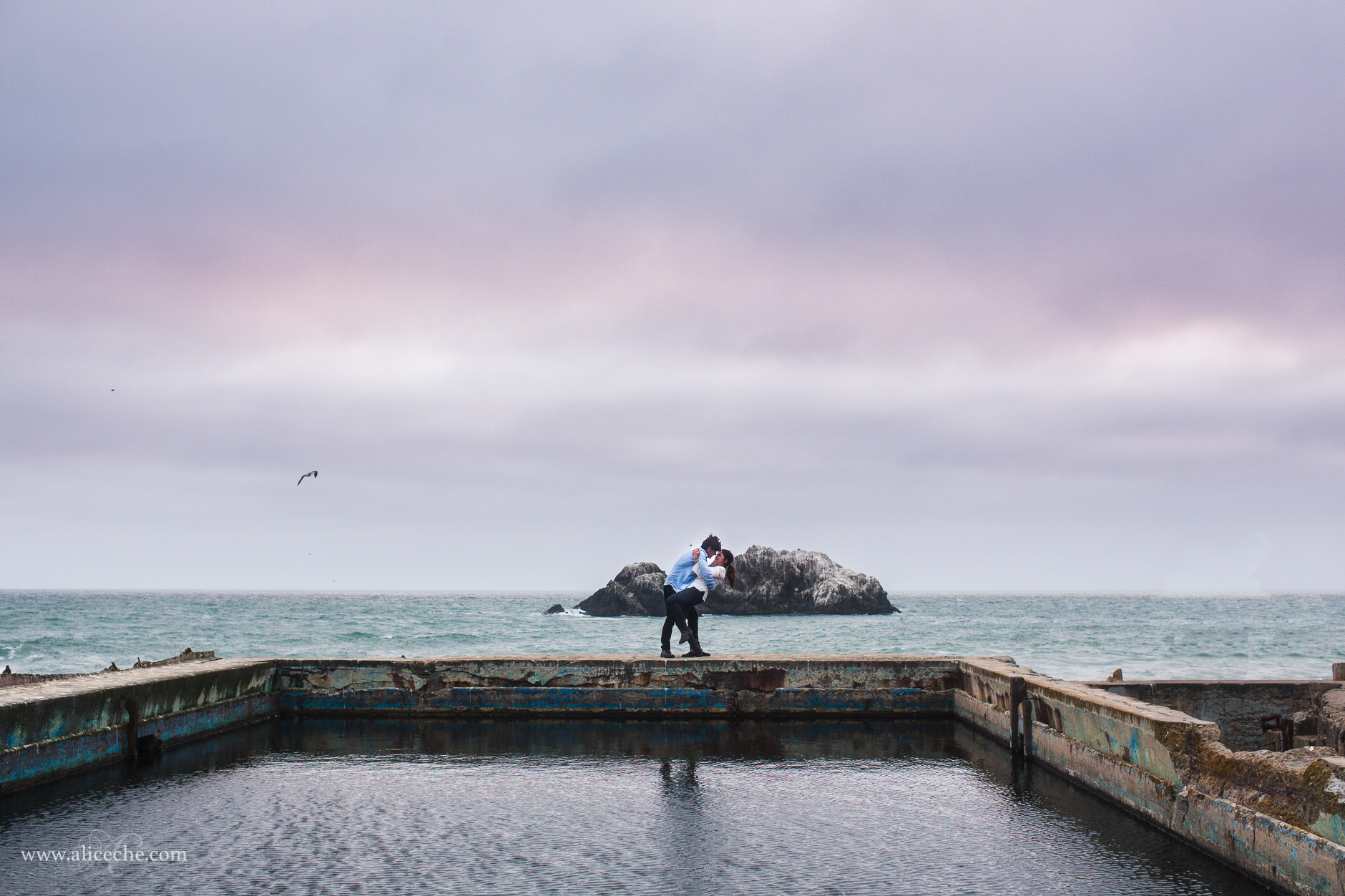 sutro baths engagement portrait san francisco guy dipping his fiance in front of the ocean