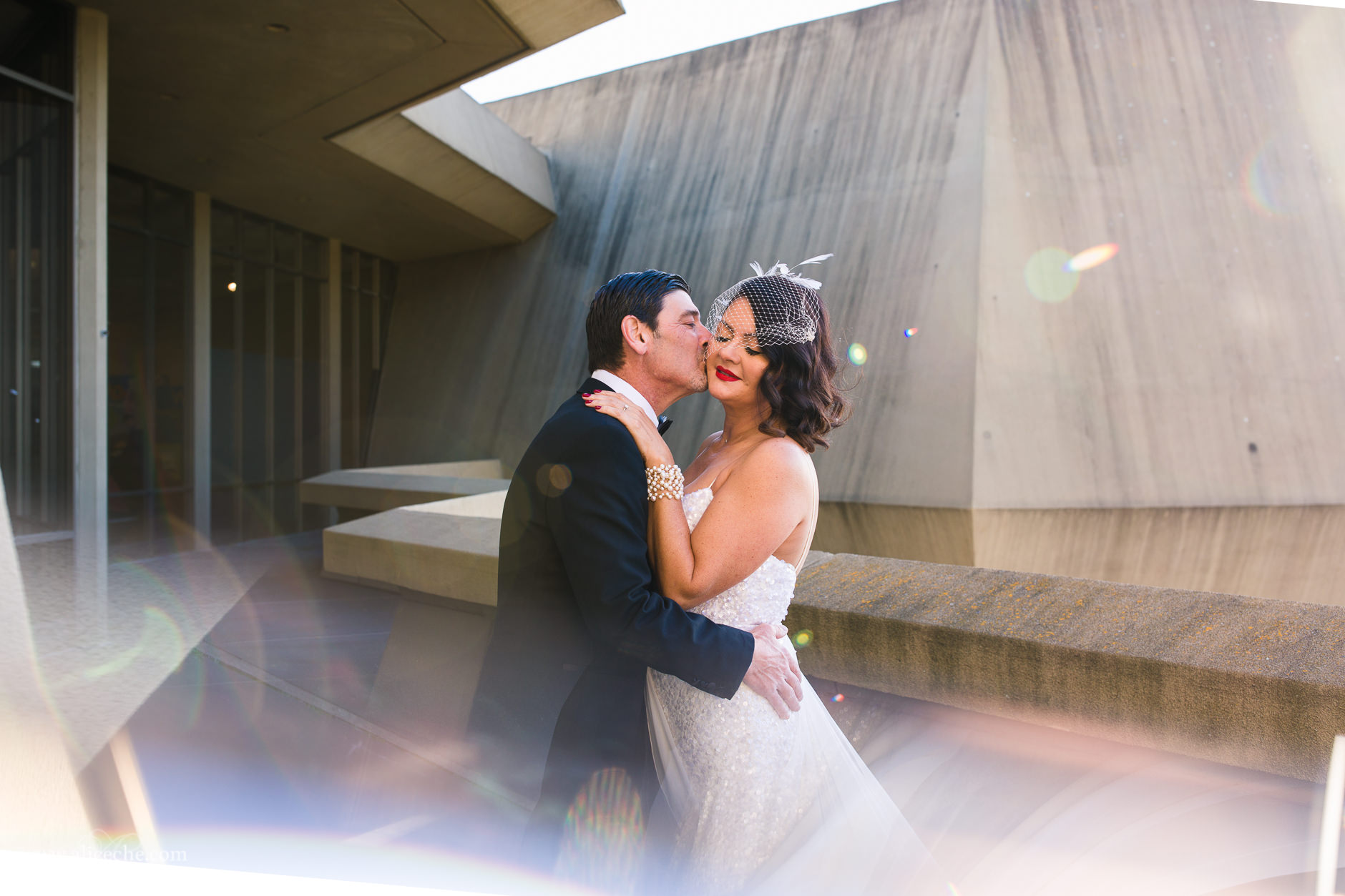 Groom kissing bride on cheek at Lawrence Hall of Science