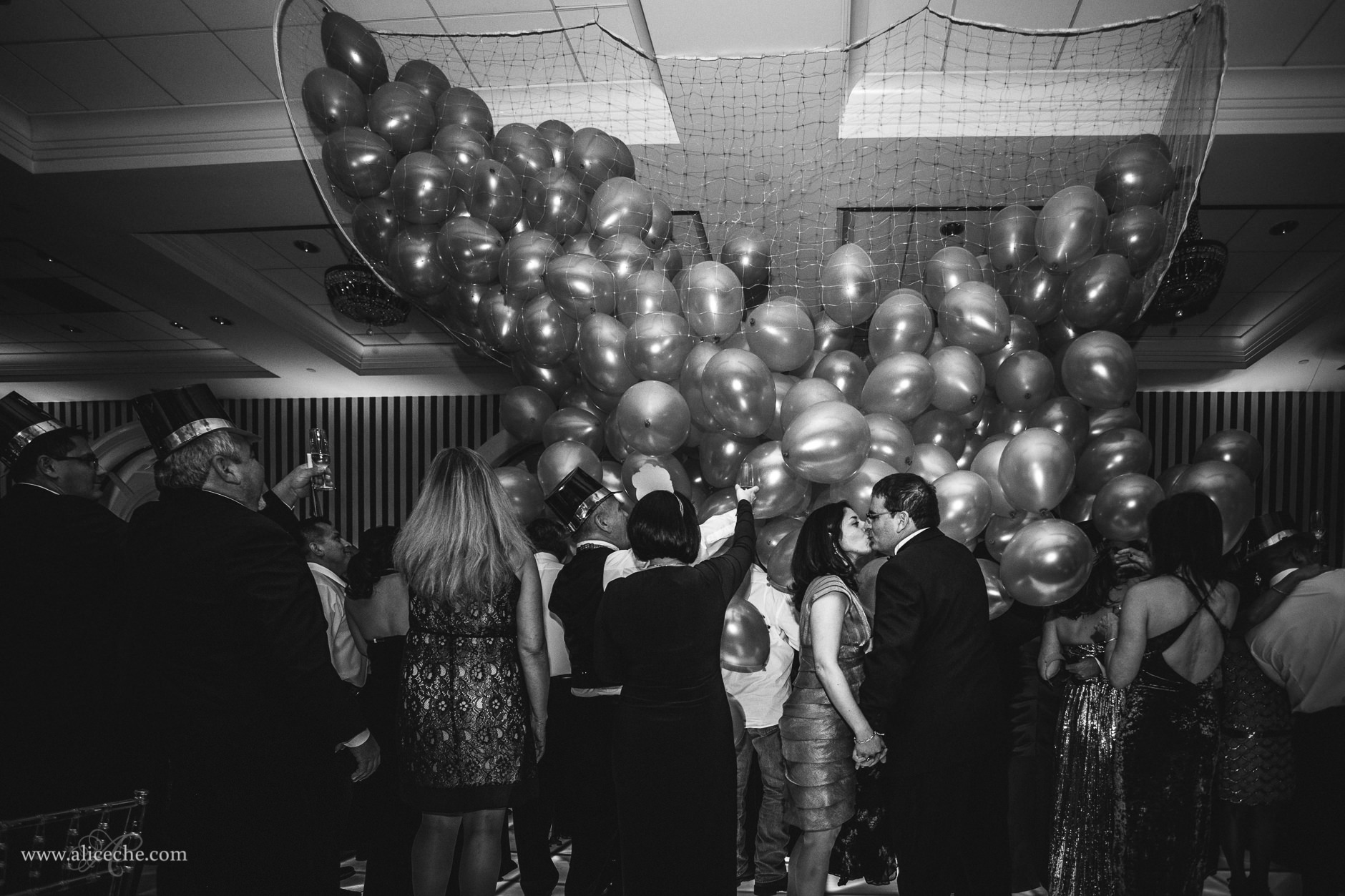 Couple kissing in front of balloon drop at NYE wedding