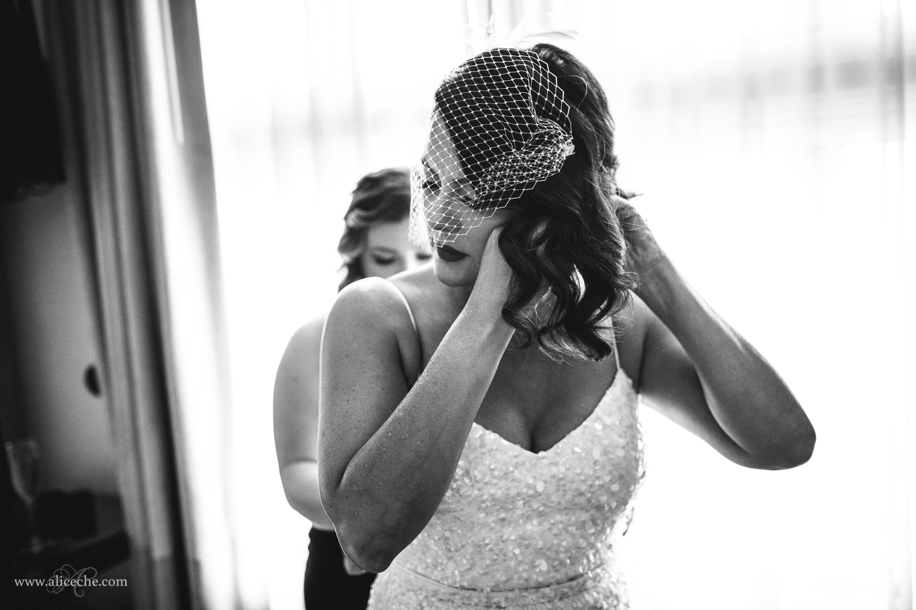Black and white picture of bride putting on earrings