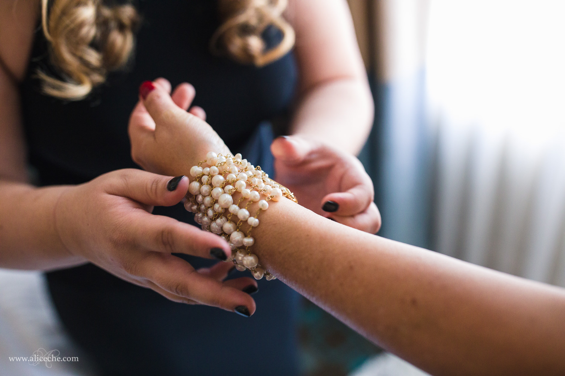 Bride's daughter helping bride put on a pearl bracelet