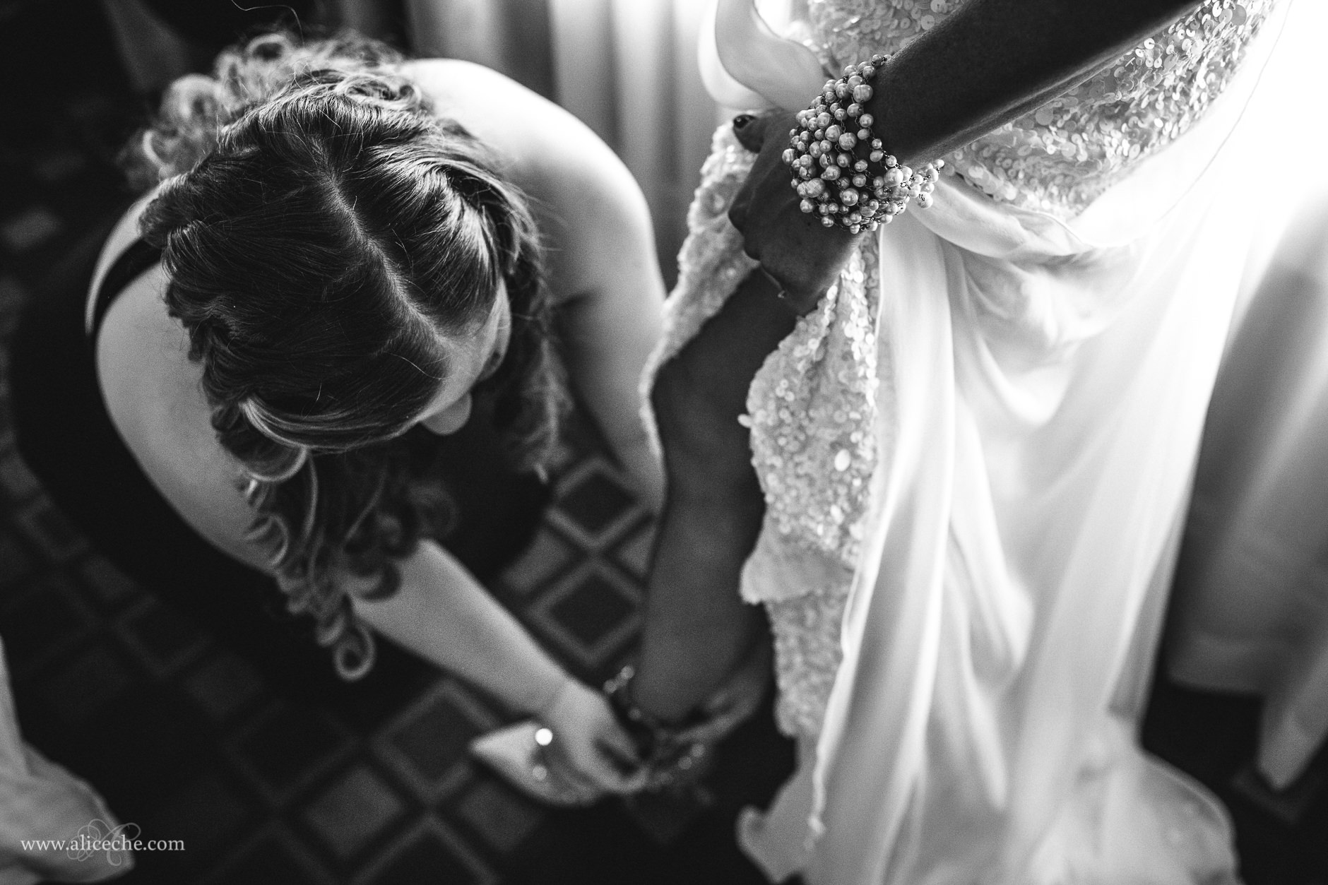 Bridesmaid helping bride put on shoes for New Year's Eve wedding in Berkeley