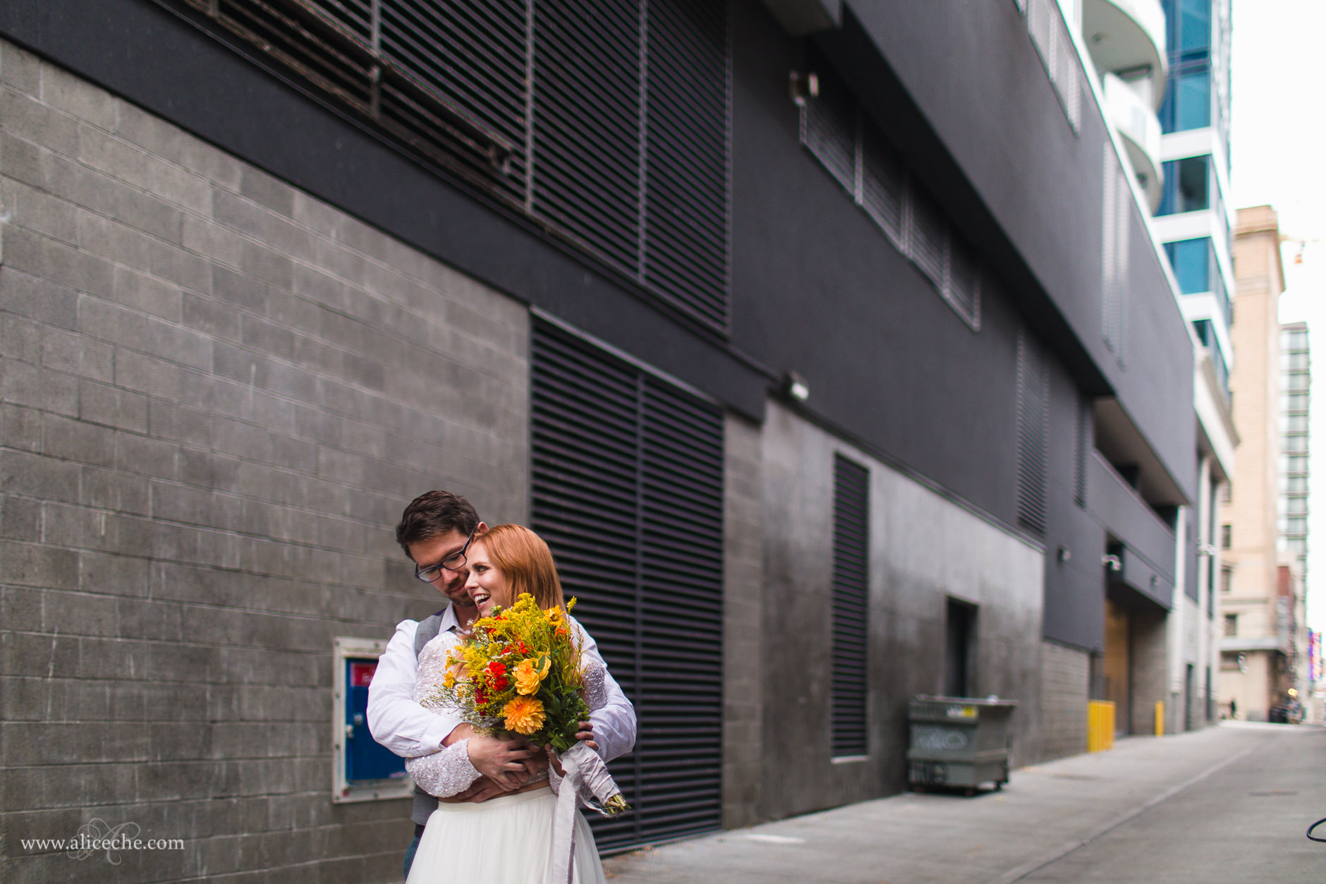 Groom hugging redhaired bride in alley