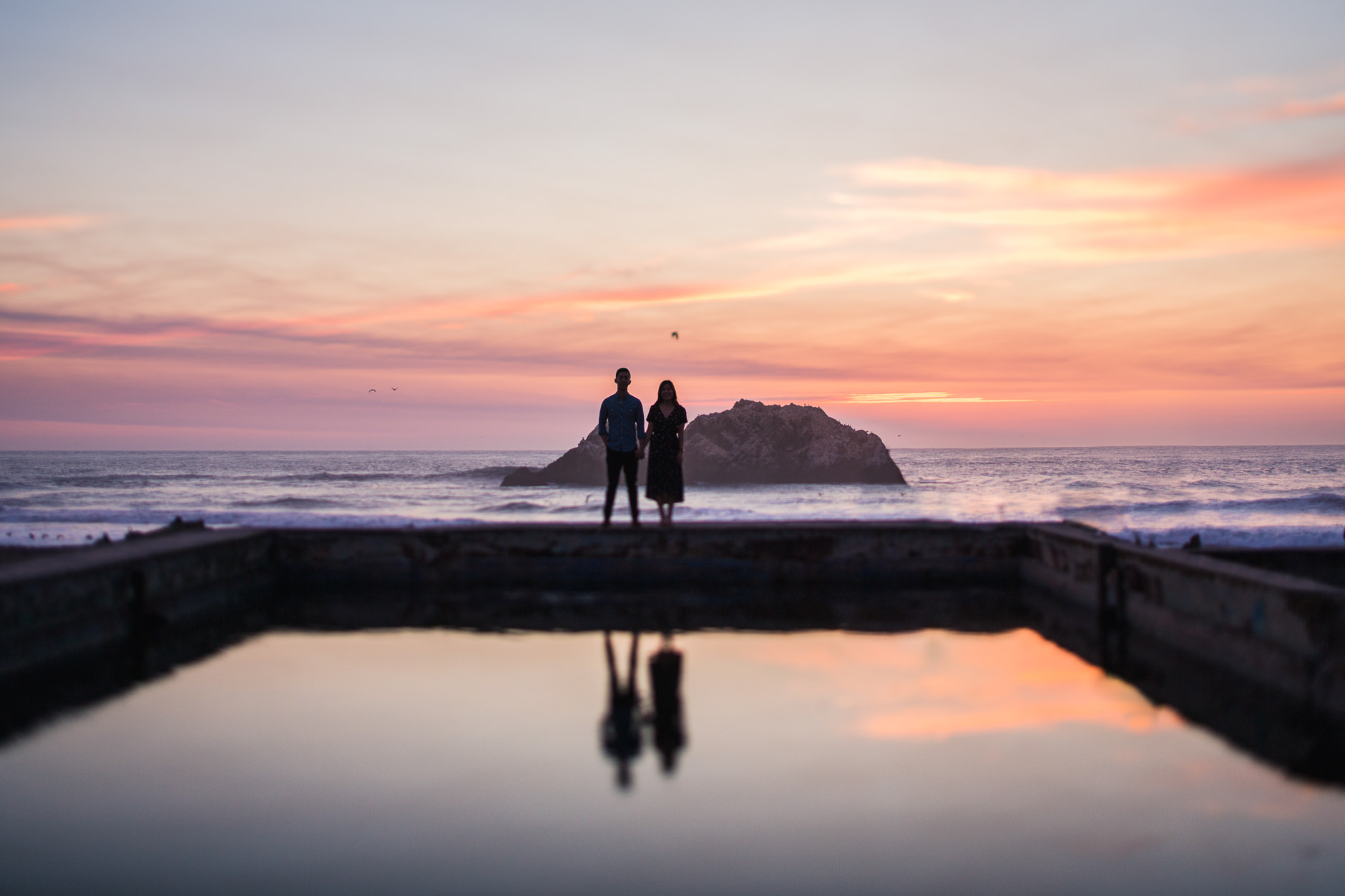 Engaged couple at Sutro Baths at sunset with beautiful reflection