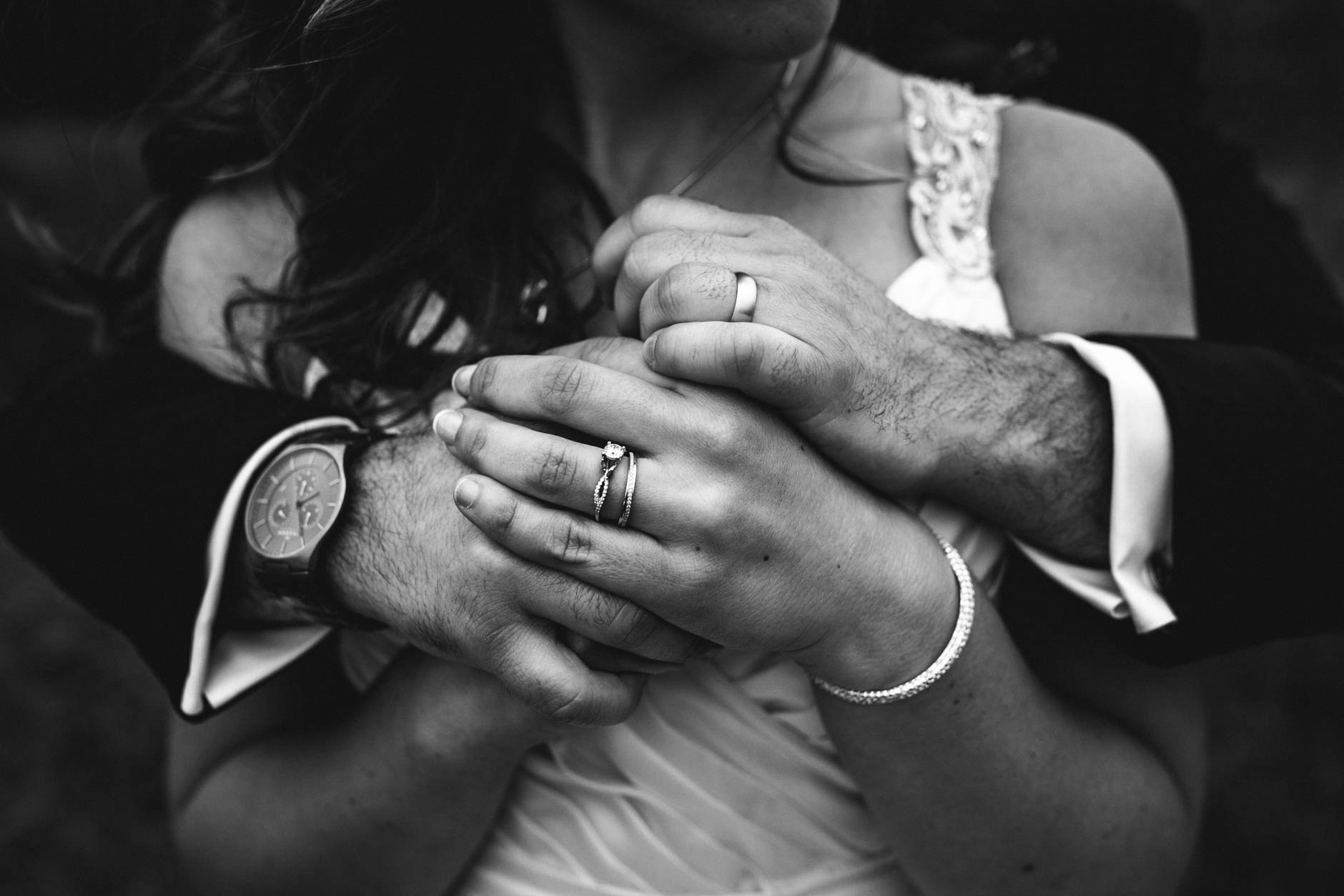Black and white photo of bride and groom's hands with rings