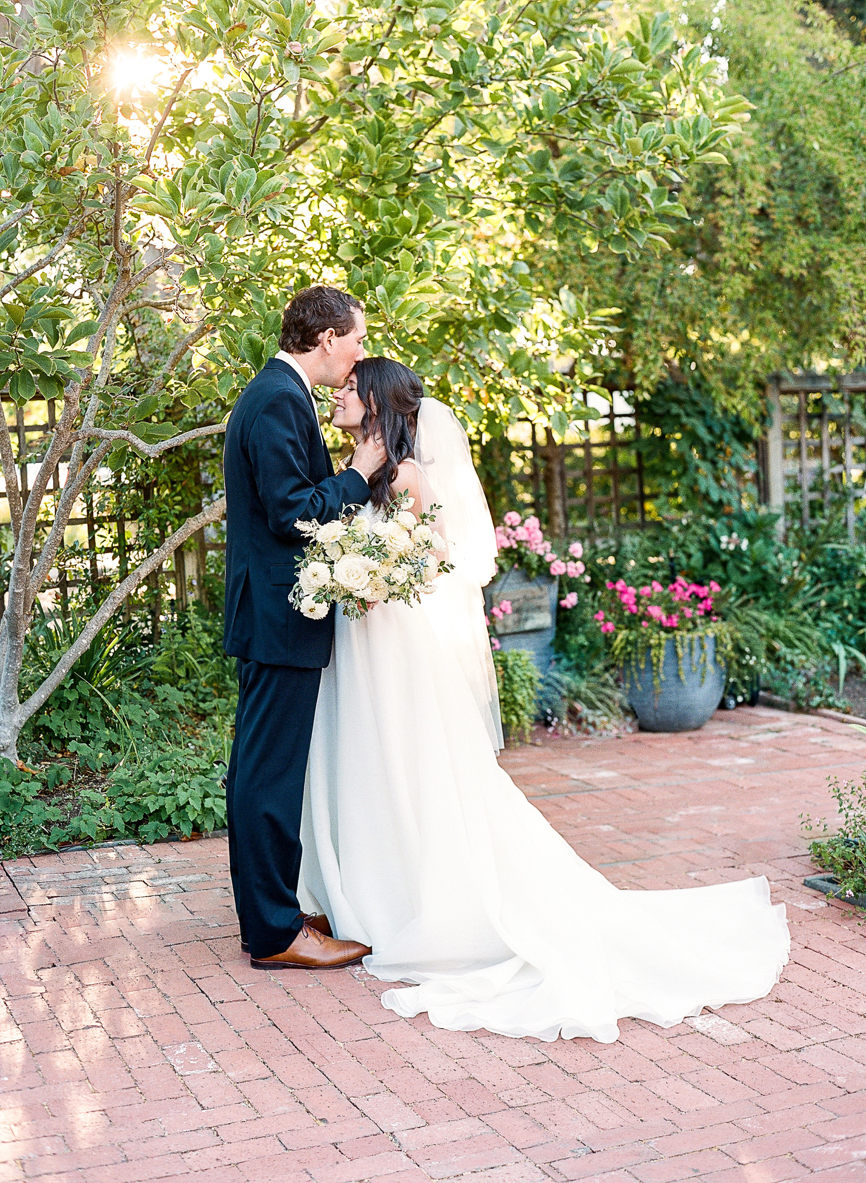 Groom kissing Bride on the forehead in the gardens of Los Altos History Museum during their wedding