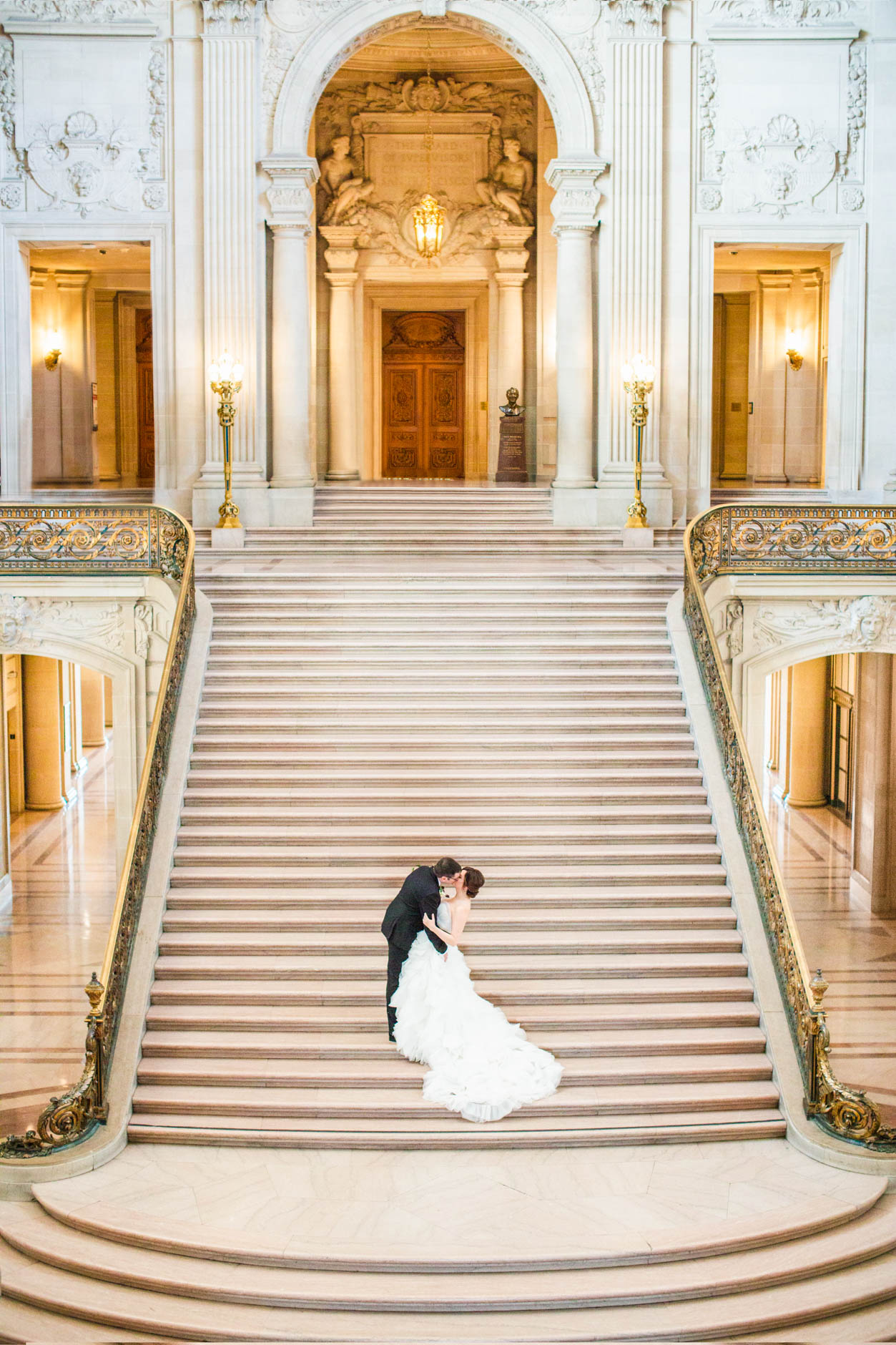 San Francisco City Hall wedding bride and groom kissing on grand staircase