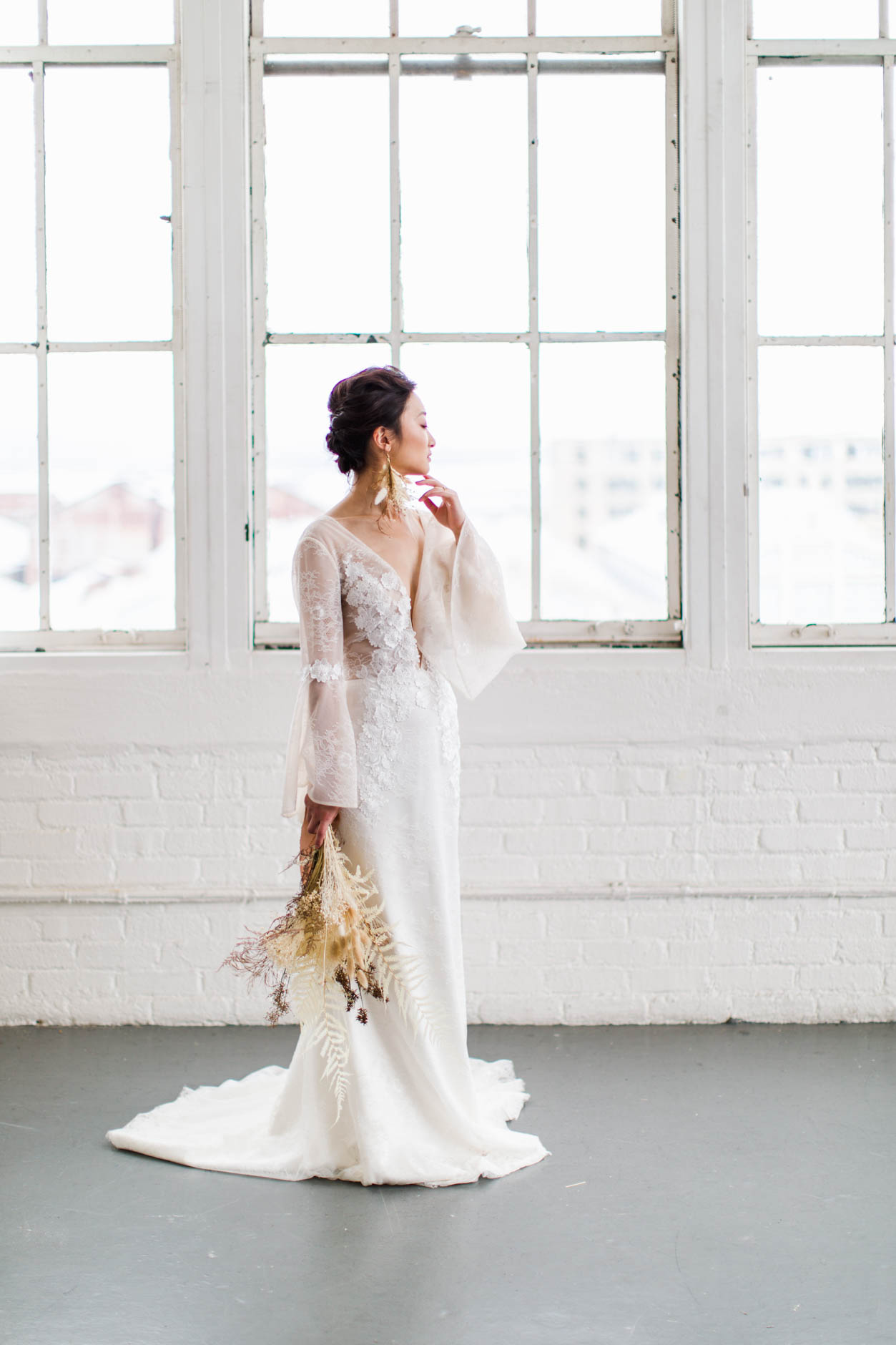 Bride standing in front of windows in modern warehouse wedding inspiration