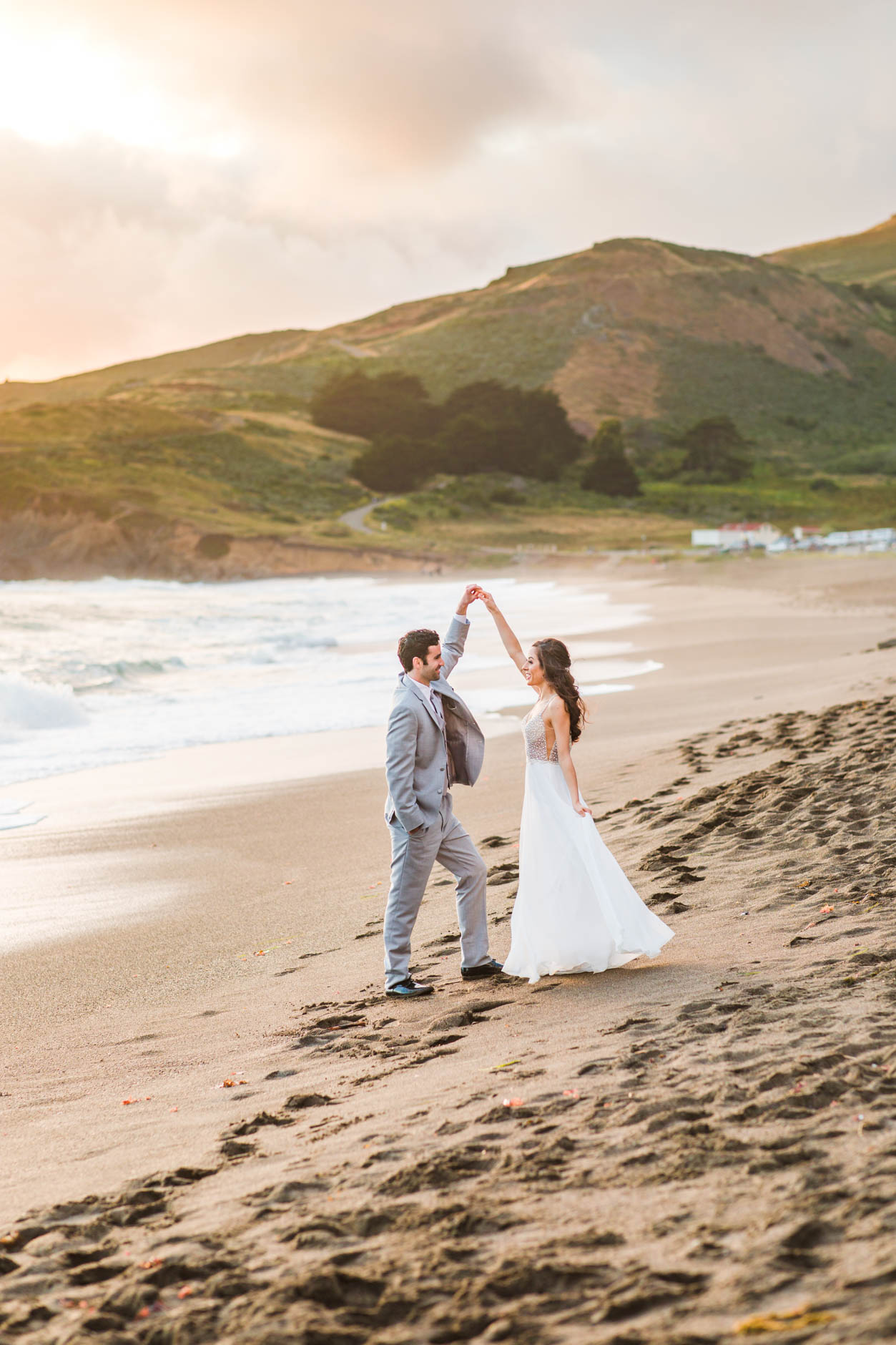 Windswept elopement photos of bride in white dress and groom in grey suit
