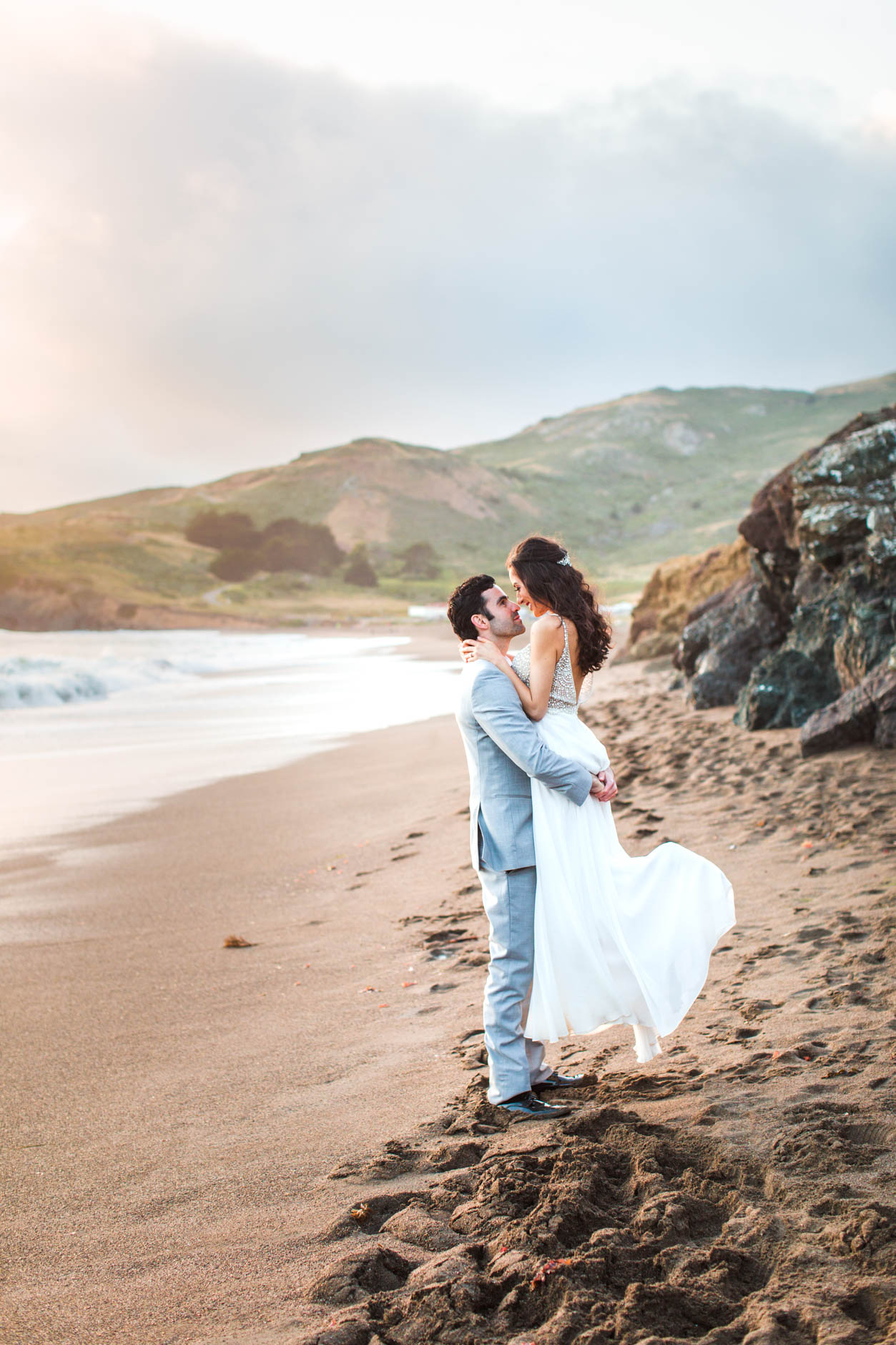 Groom picking up bride on Rodeo Beach elopement photos