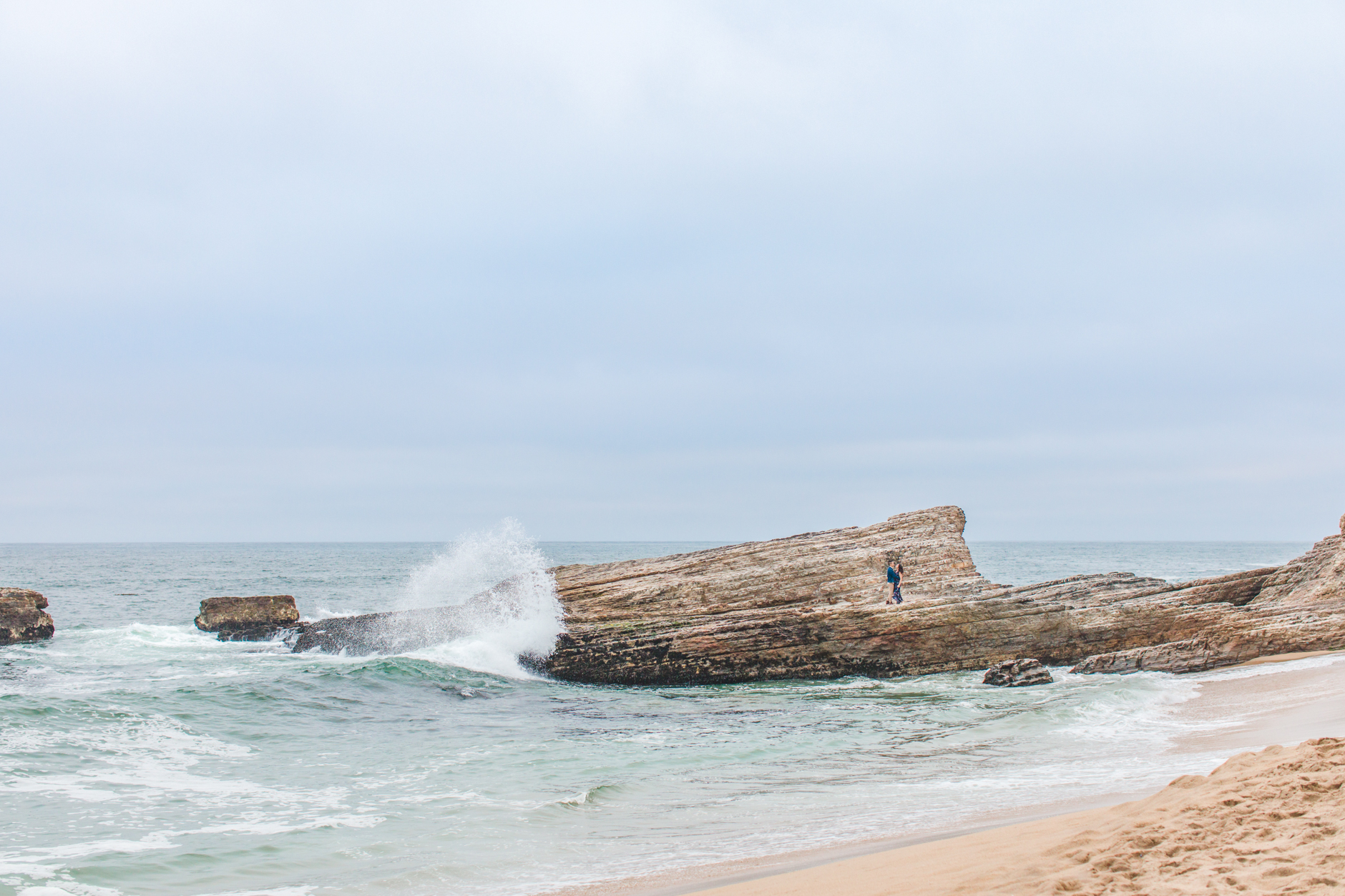 Bride and Groom Kissing on Rocks while Waves Splash against rocks at Coast Dairies State Park engagement session