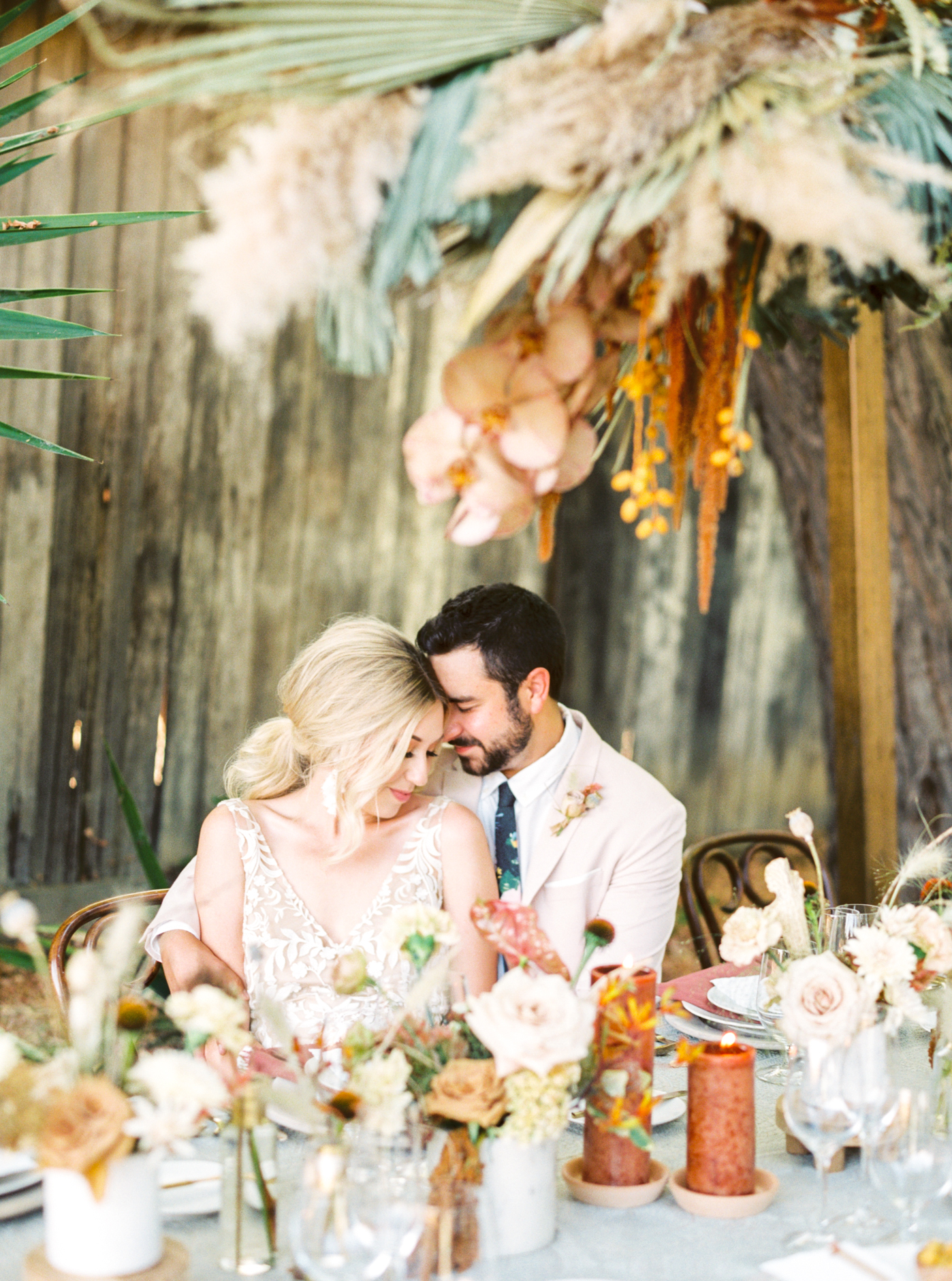 Bride and Groom cuddling at reception table under hanging floral installation at Reinstein Ranch wedding photographed by Alice Che photography