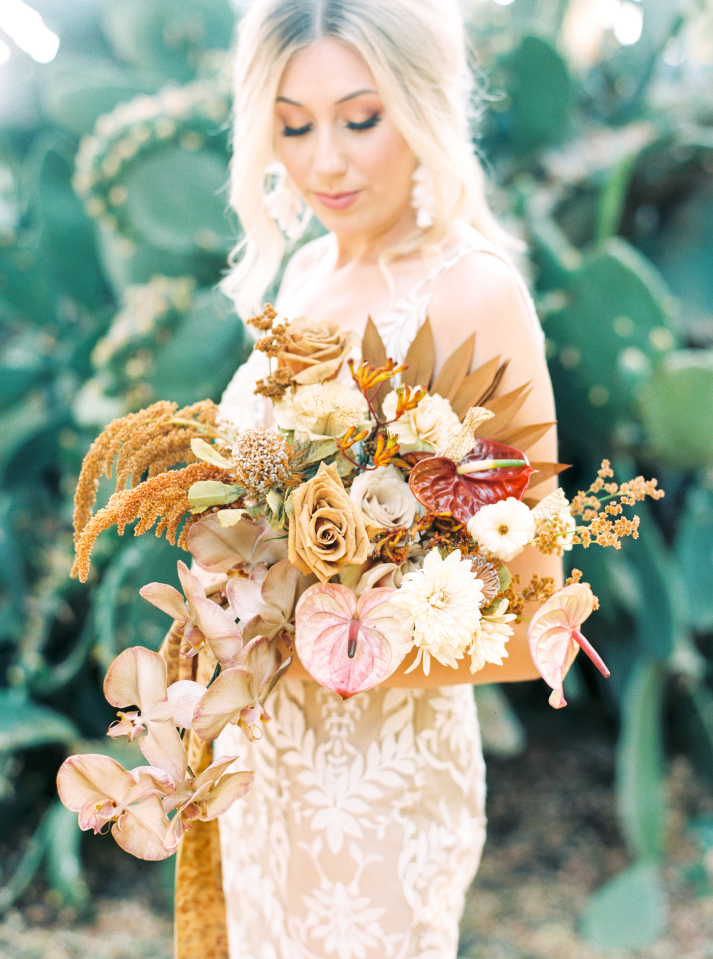 Bride holding gorgeous bouquet filled with tans and terracottas in front of cactuses at Reinstein Ranch Wedding photographed by Alice Che Photography